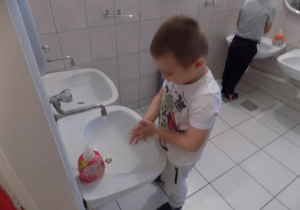 Arthur ćwiczy prawidłowe mycie rąk przy umywalce.